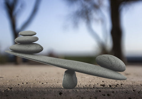 Steine balancieren auf Wippe, Symbol für Gleichgewicht, Natur im Hintergrund, Balance-Konzept