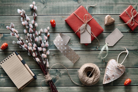 Geschenkverpackung aus Naturmaterialien, Notizblock, Kordel, Herzen und Kätzchenzweige auf Holztisch