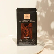 Pflanzenhaarfarbe Packung warm flame red auf weißem Teller, natürliches Licht