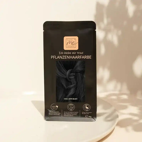 Natürliches Pflanzenhaarfarbe Pulver Cool Deep Black im schwarzen Beutel auf weißem Teller
