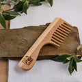 Holzkamm aus Buchenholz mit breiten Zähnen auf Steinplatte, Naturkosmetik Accessoire