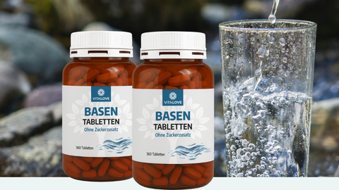 Zwei Dosen Basen Tabletten ohne Zusatzstoffe neben einem Glas Wasser für den Säure-Basen-Ausgleich