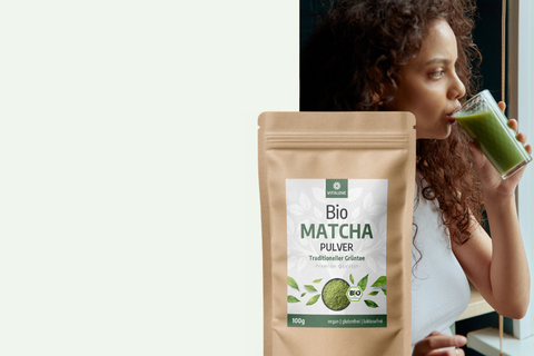 Frau trinkt Matcha-Getränk neben VITALOVE Bio Matcha Pulver 100g Beutel