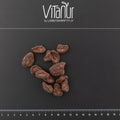 Bio Schokobohne Stücke auf schwarzem Hintergrund mit Vitanur Logo und Zentimeterskala