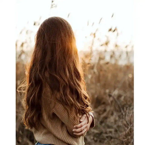 Frau mit langen braunen Haaren im Sonnenlicht auf einem Feld, Natur, Herbststimmung
