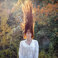 Frau mit langen, fliegenden roten Haaren im Herbstwald, natürliches Licht, Modefoto