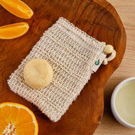 Naturseife und Seifensäckchen aus Sisal auf Holzbrett mit frischer Orange